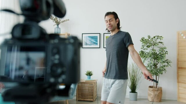 Sports vlogger is recording video with home training jumping with skipping rope and talking to camera smiling enjoying healthy activity. People and vlogging concept.