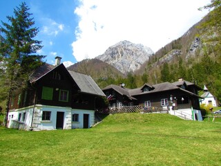 Fototapeta na wymiar View of mountain lodge at Kamnsika Bistrica in Slovenia and forest covered hills and mountain peaks of Kamnik-Savinja alps behind
