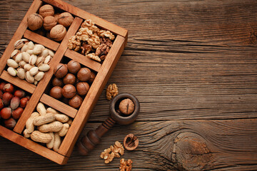 Various nuts selection: peanuts, hazelnuts, chestnuts, walnuts, pistachio and pecans in wooden box. Top view with space for your text