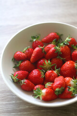 Bowl of fresh strawberries on wooden table. Selective focus.