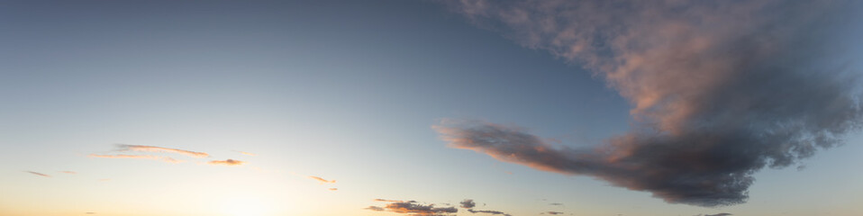 Panoramic View of Cloudscape with puffy sky and clear sunny sunlight during a colorful sunset or...