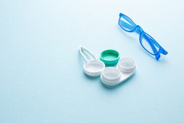 Fototapeta na wymiar Glasses and accessories for contact lenses: a container for lenses and tweezers on a blue background