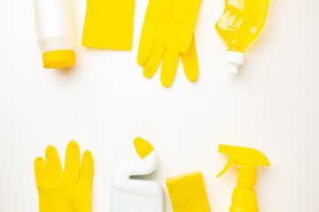Plastic bottles of cleaning products, sponge and glove on white background with space for text.