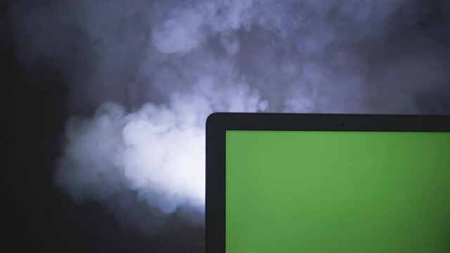 Ordinateur portable avec fond vert sur fond noir isol&eacute; avec de la fum&eacute;e 
