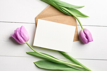 Greeting card mockup with envelope and tulip flowers on white wooden background