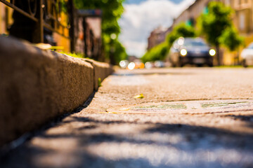 Sunny day after rain in the city,  the headlights of the approaching car on the road lit by the...