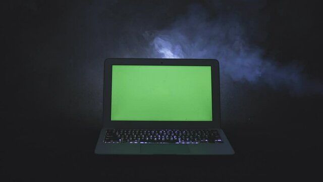 Ordinateur portable avec fond vert sur fond noir isol&eacute; avec de la fum&eacute;e 