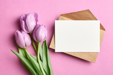 Greeting card mockup with envelope and tulip flowers bouquet on pink background