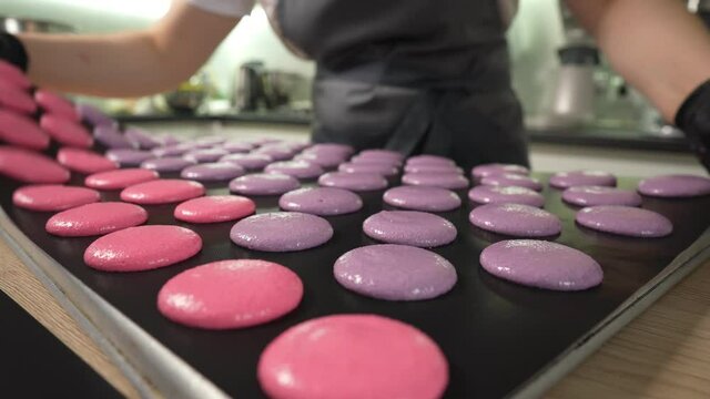 Process Of Making macaroon at home. Shot of hands of female pastry chef holding white macaron with ganache and squeezing red fruit jam from bag. Nature pastry macaroons. High quality 4k footage