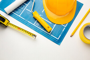 Floor plan, hard hat, tape measure, construction tools on a white background