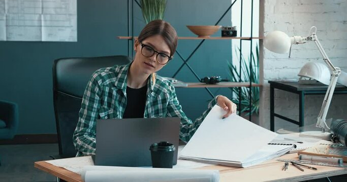 Architect drawing blueprints in office. Engineer sketching a construction project. Architectural plan. Close-up portrait of beautiful woman concentrated on work. Business construction concept.