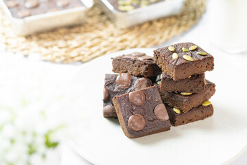 flourless pumpkin chocolate brownies set on white cafe table.