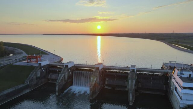 Hydroelectric dam power plant station production of energy supply for city life. Aerial view during colorful sunset big lake natural unpolluted landscape