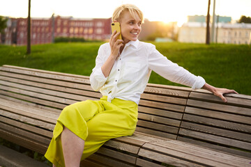 Smiling female millennial enjoying positive international conversation for talking with parents during leisure pastime, cheerful hipster girl phoning via cellular device using roaming internet