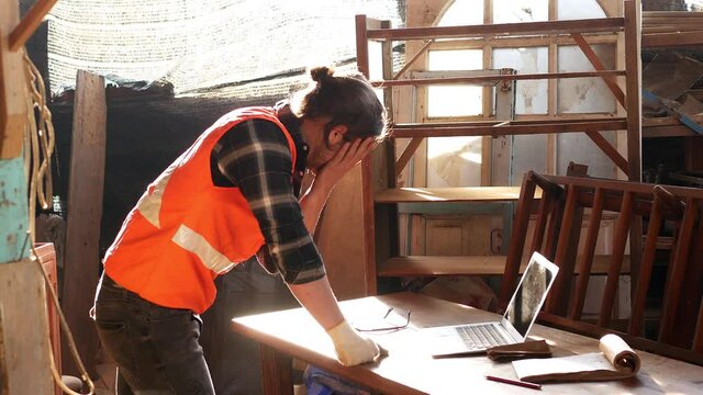 Young Caucasian carpenter is stress and regrets that the customer cancels the order for furniture repair. Due to the economic downturn During the coronavirus,covid-19 outbreak all over the world.
