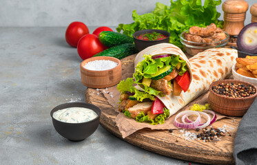 Burrito with chicken on the background of ingredients on a gray background.