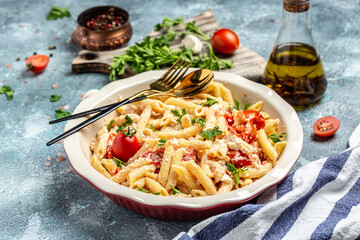 Baked feta pasta with cherry tomatoes, olive oil and herbs in a pan. Trend mixing macaroni and cheese. Food recipe background. Close up