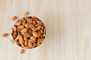 Almond nuts in a white bowl on wooden background, top view, flat lay, top-down, selective focus.copy space.