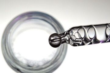 a cosmetic pipette filled with a bubbling liquid and a bottle. close-up.