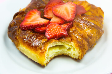 Bitten Puff pastry bun or roll. Cake with fresh strawberries. Delicious sweets temptation and...
