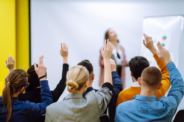 Group of young people sitting at a conference together raised hands to express their views. Business group meeting seminar training concept. Planning, analysis, collaborate work in teamwork.