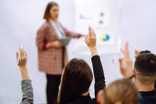 Group of young people sitting at a conference together raised hands to express their views. Business group meeting seminar training concept. Planning, analysis, collaborate work in teamwork.