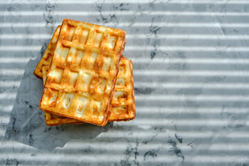 Waffles on kitchen marble countertop, morning breakfast, sunlight through blind.