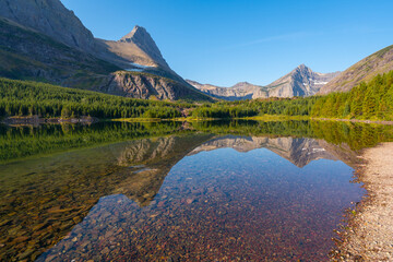 Sunny day by Bullhead lake in the Glacier National Park. Mountain range reflection in water...