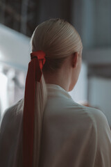 Female hairstyle of blonde hair elegant ponytail with red ribbon. Back view - obrazy, fototapety, plakaty