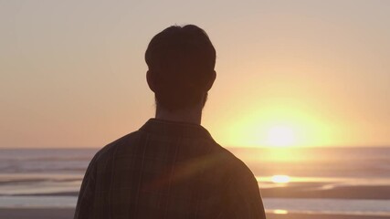 Young unrecognisable man contemplating a beautiful sunset by the sea: Freedom in a lonely beach - Powered by Adobe
