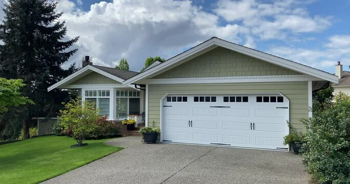 Establishing shot of one story luxury house with garage door, big tree and nice landscape in Vancouver, Canada, North America. Day time on May 2021. ProRes 422 HQ.