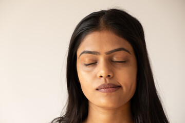Closeup shot of a beautiful Asian girl with closed eyes isolated on a white background © Media Nation/Wirestock