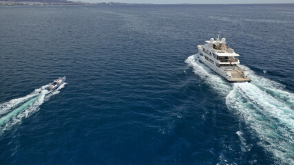 Aerial drone photo of luxury yacht cruising in deep blue sea near Mediterranean Aegean island