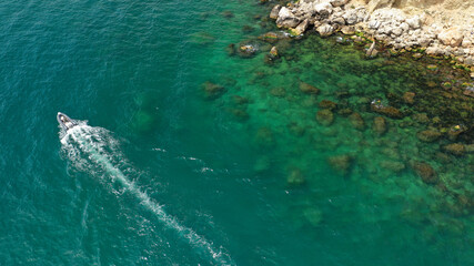 Aerial drone photo of small inflatable speed boat cruising near tropical exotic island with emerald crystal clear sea