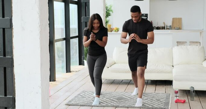 African American couple doing lunges exercise together at home