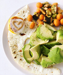 beautiful delicious breakfast of scrambled eggs, avocado, Japanese snacks, mustard in the form of a heart