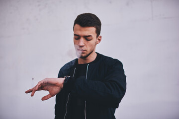 Thoughtful young man checking time on watch