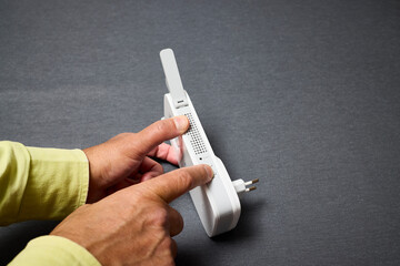 Man hands using a wifi repeater to extend network coverage