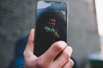 Crop man closeup showing self portrait on smartphone