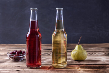 fruit beer in bottles, pear and cherry on a wooden table