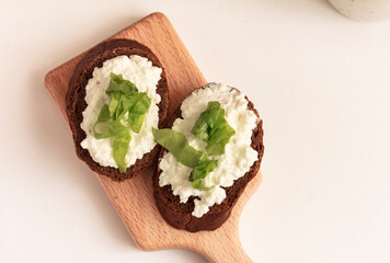 Open Rye Sandwiches with cottage cheese and green salad on cutting board on white background. Easy snack idea. Bio, organic, natural ingredient. Top view, stock photo