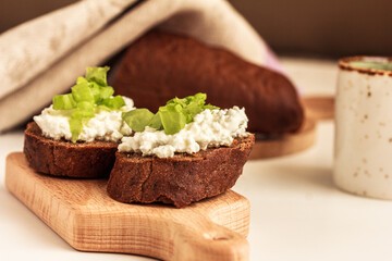 Open Rye Sandwiches with cottage cheese and green salad. Easy breakfast idea. Side view, stock photo.