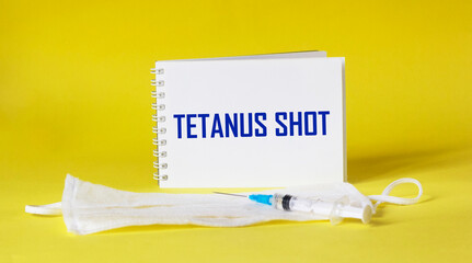 tetanus shot text is written on a notepad and a yellow background, next to a medical mask and a...