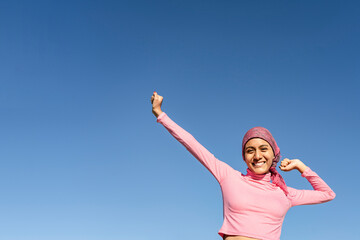 Young woman with cancer with gestures of victory and joy in the face of the disease. Celestial...