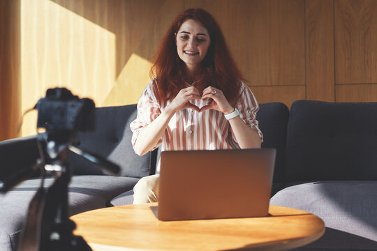 Front view of business woman recording video lecture with digital camera, tripod and laptop