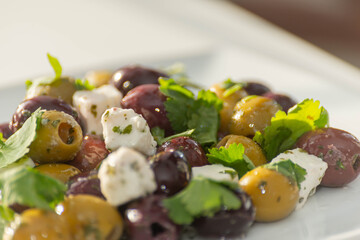 Fresh Greek salad based on green and black olives with pieces of white feta cheese and parsley