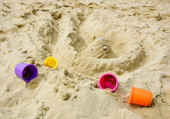 Fototapeta na wymiar Sand castle on the beach four colorful molds. Vacation concept.