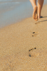 a man walks along the sand along the seashore and leaves traces of bare feet