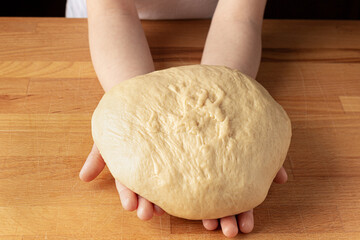 baby holding dough on a wooden board