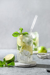 Classic mojito on gray background. Summer mojito made of lime, mint, and ice cube. Vertical orientation. Close up.